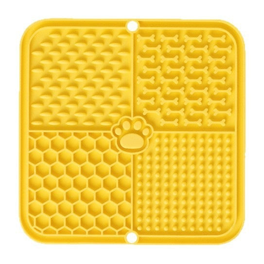 The dog licks the pet feeding pad on the table.
